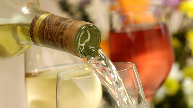 Close up of white wine bottle pouring into wine glass