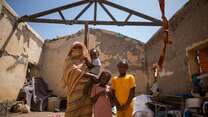 Altuma stands in her temporary house with her three children.