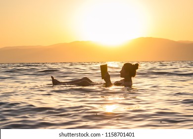 floating in the dead sea sunset, Israel Arkivfotografi