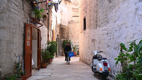 Bari, Italy, 12 of February 2022, Narrow street with stone in Bari Vecchia (Old Town), cyclist, scooter Redaksjonell arkivvideo