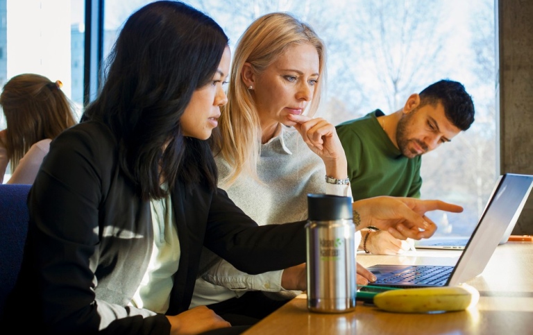 Tre studenter som pluggar i biblioteket