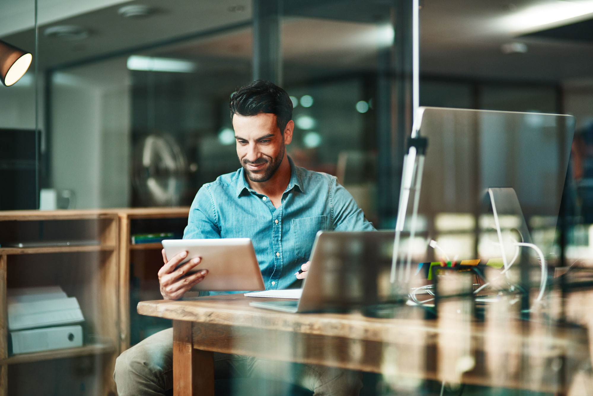 Software employee sitting at a workstation reading from a tablet