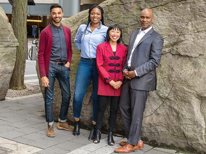 A group of four racially diverse people standing in front of rock