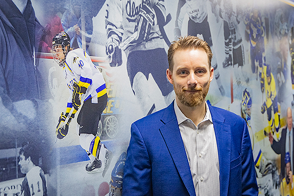 Ryan Muspratt, recipient of the 2024 Distinguished Alumnus Award from the UAF Alumni Association, visits a collage of Alaska Nanook hockey images on a wall at the Carlson Center in 2024.