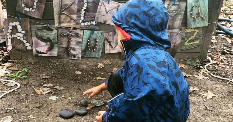 Small child playing with rocks in outdoor classroom