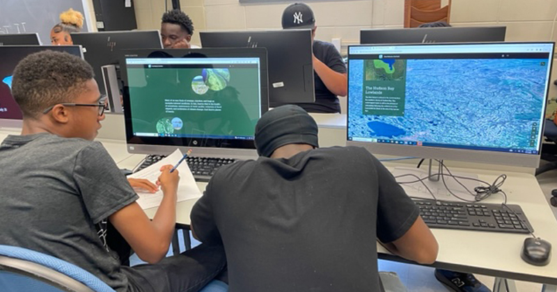 Two young men working together at computer screens