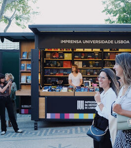 Stand da Imprensa da Universidade de Lisboa na Feira do Livro com pessoas a passar