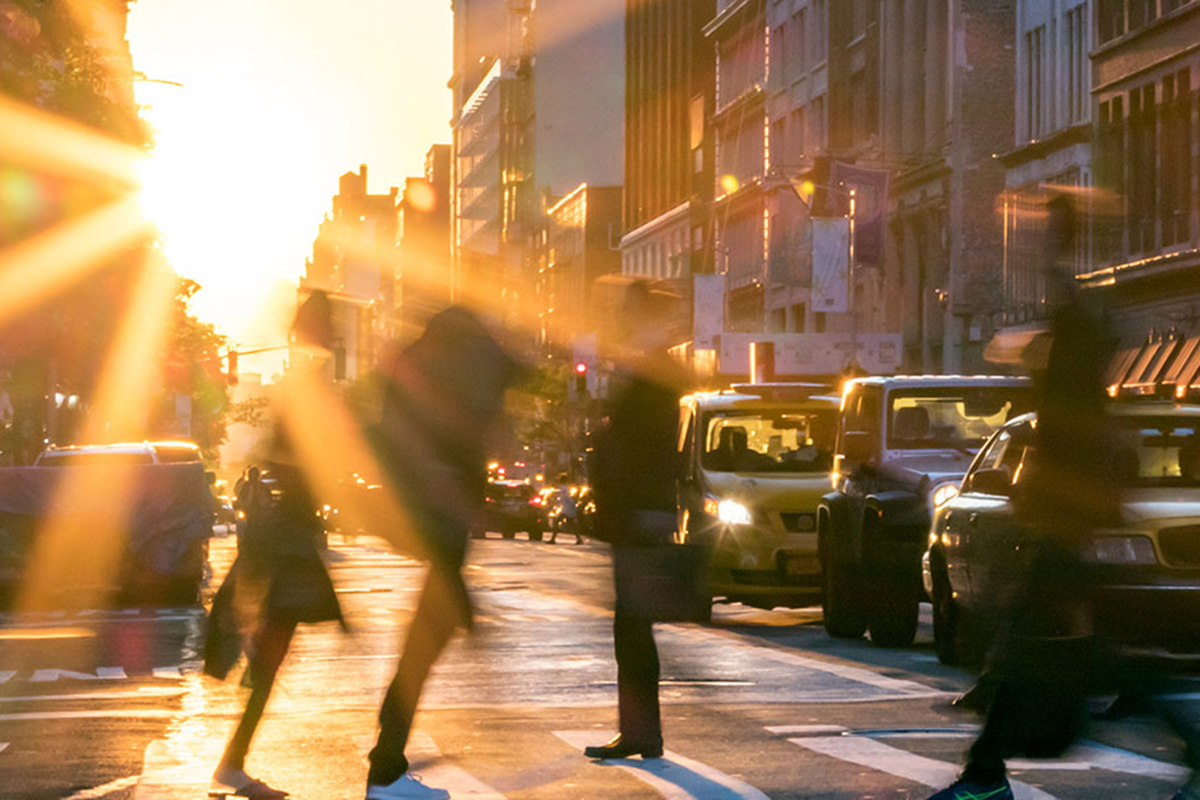 people on a crosswalk against the sun at sunset