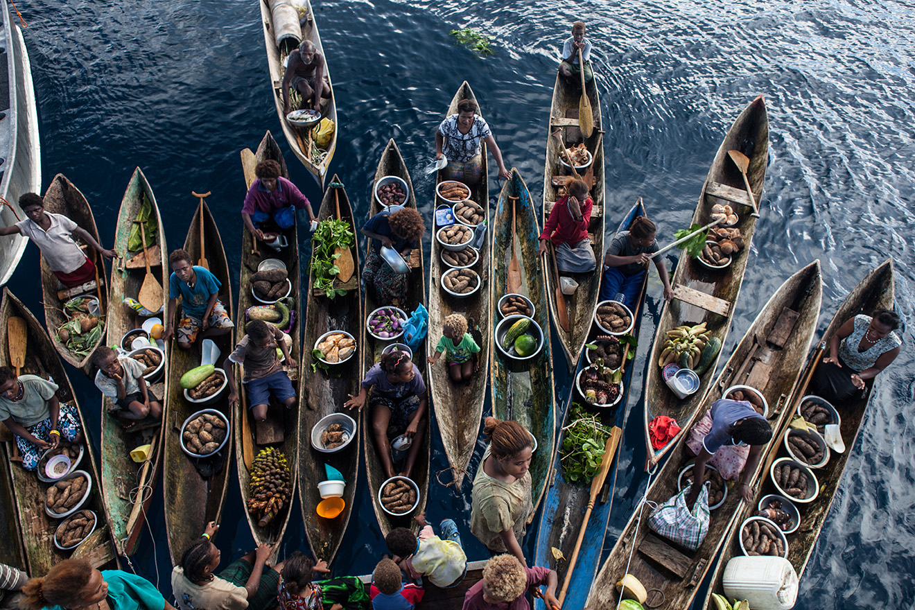 people selling fresh produce in a floating market of dugout canoes