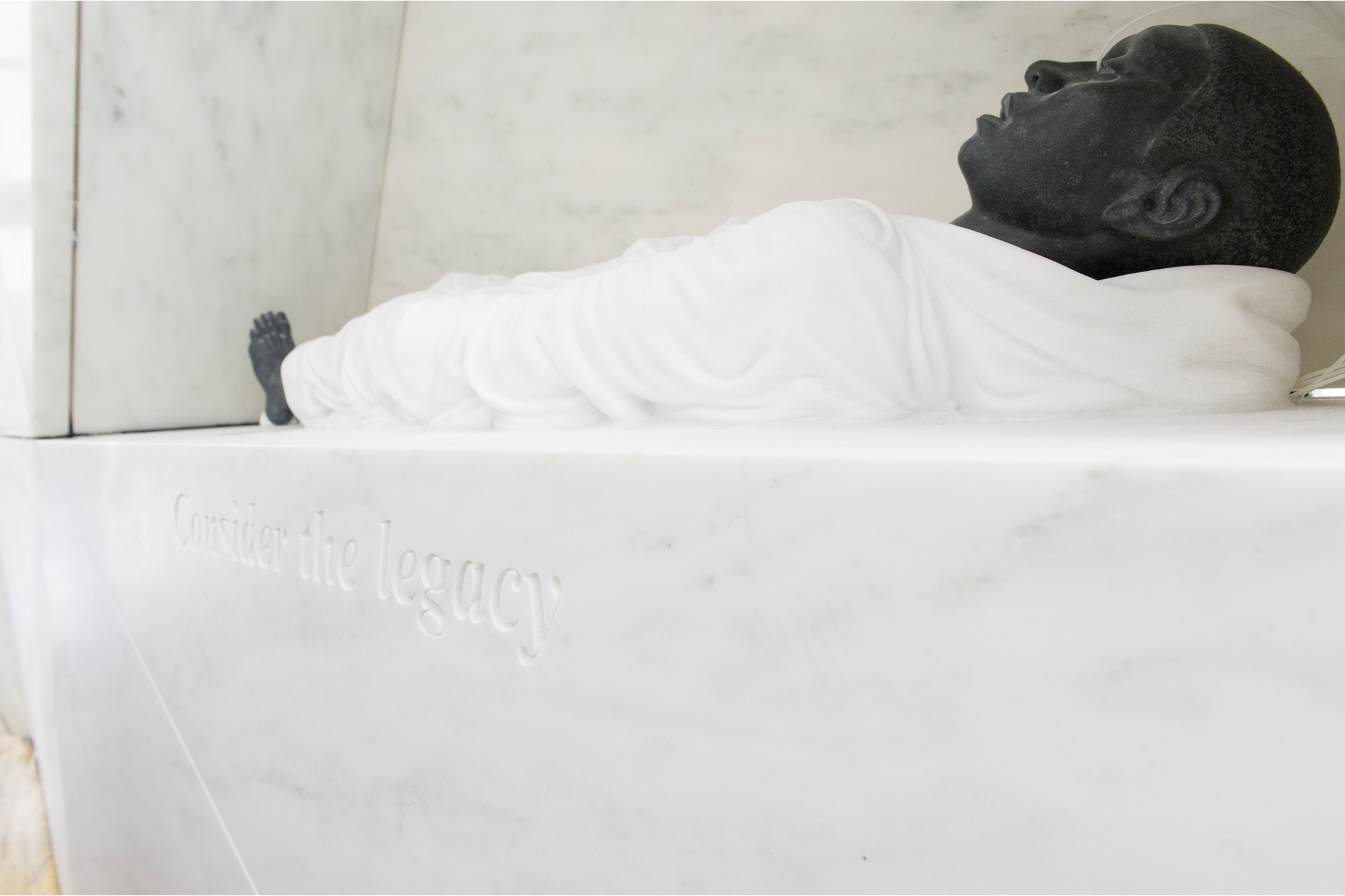 A view of the sculpture “The Ark of Return” with a man lying on a white marble structure. The statue, at the UN headquarters in New York, honors the victims of slavery and the transatlantic slave trade.