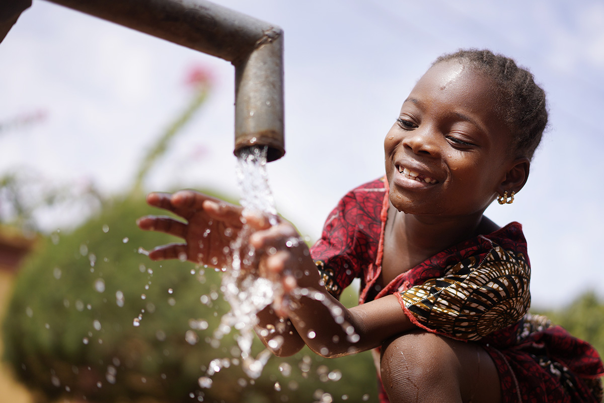 girl washing hands in a water pipe