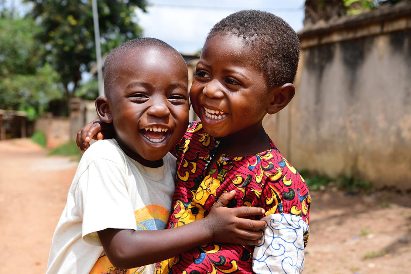 Deux garçons souriants se prennent dans les bras.