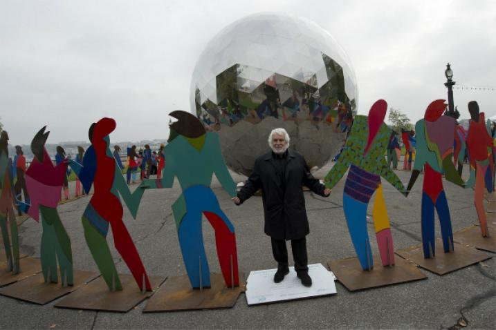 Un artiste tient par la main des statues colorées