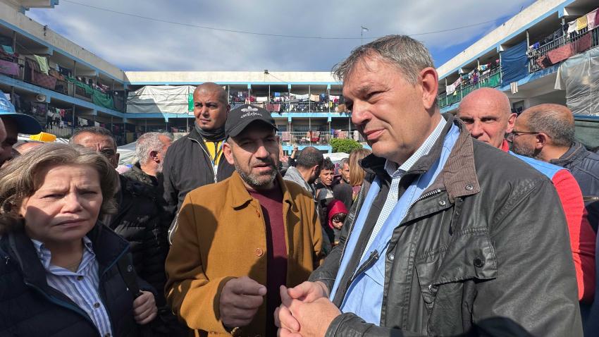 Lazzarini talking with people in a courtyard of a school that has been turned into makeshift housing. The space is overcrowded with people and hanging laundry everywhere.