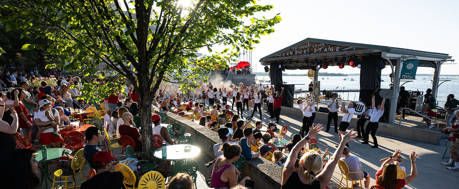 A crowd enjoys the UW Spirit Squad and members of the UW Marching Band as they perform on a summer day at the Memorial Union Terrace.