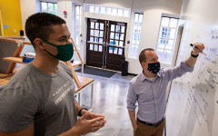 A student and staff member Graham Henshaw working at a white board in the Entrepreneurship Hub at Tribe Square