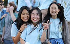 Smiling person posing with a peace sign with their fingers at a Tribe football game in Zable Stadium