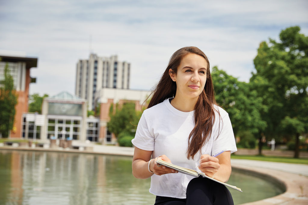 Female student sitting outside reading.